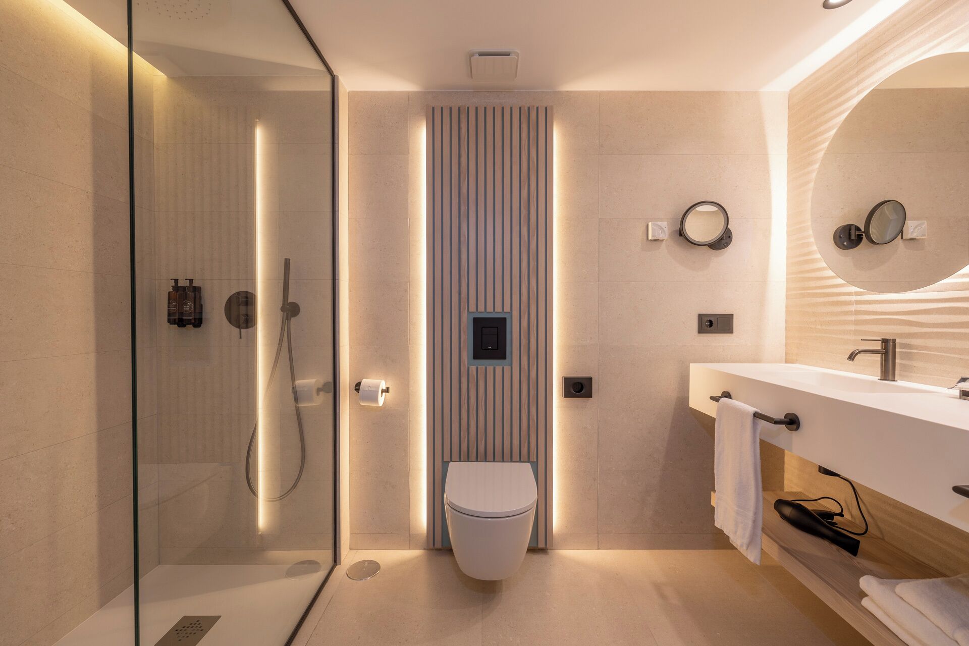 Un baño moderno con ducha envuelta en vidrio, inodoro y tocador con espejo.