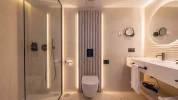 Un baño moderno con ducha envuelta en vidrio, inodoro y tocador con espejo.