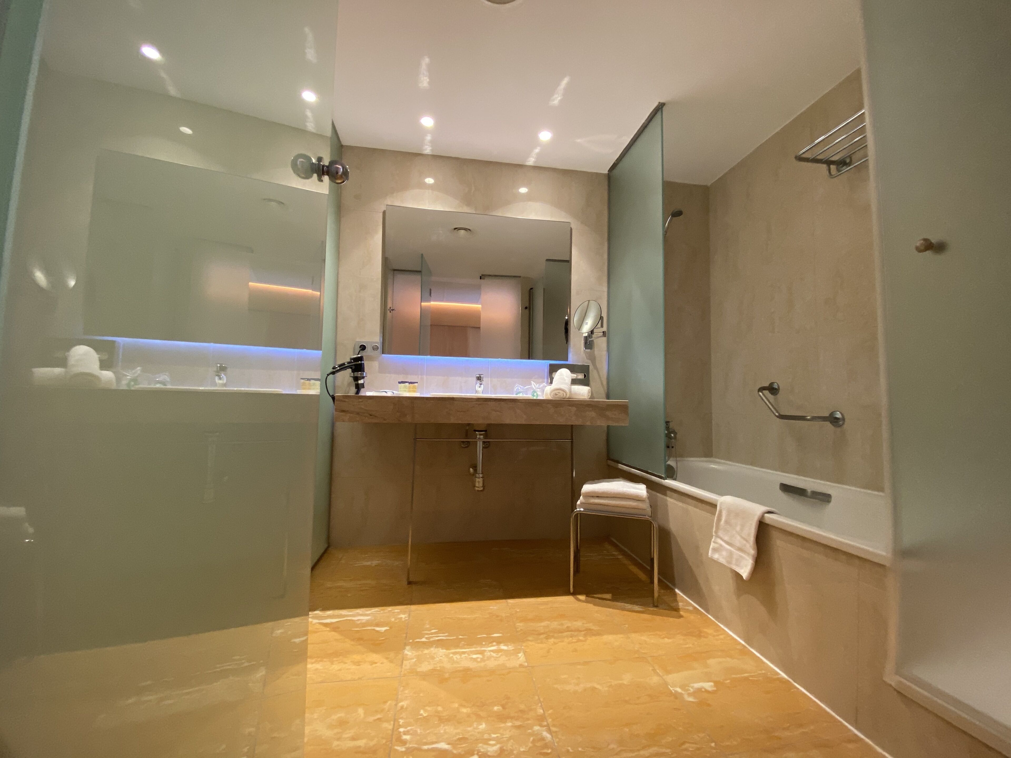 A modern bathroom with a glass-enclosed shower, a vanity with a mirror, and a bathtub.