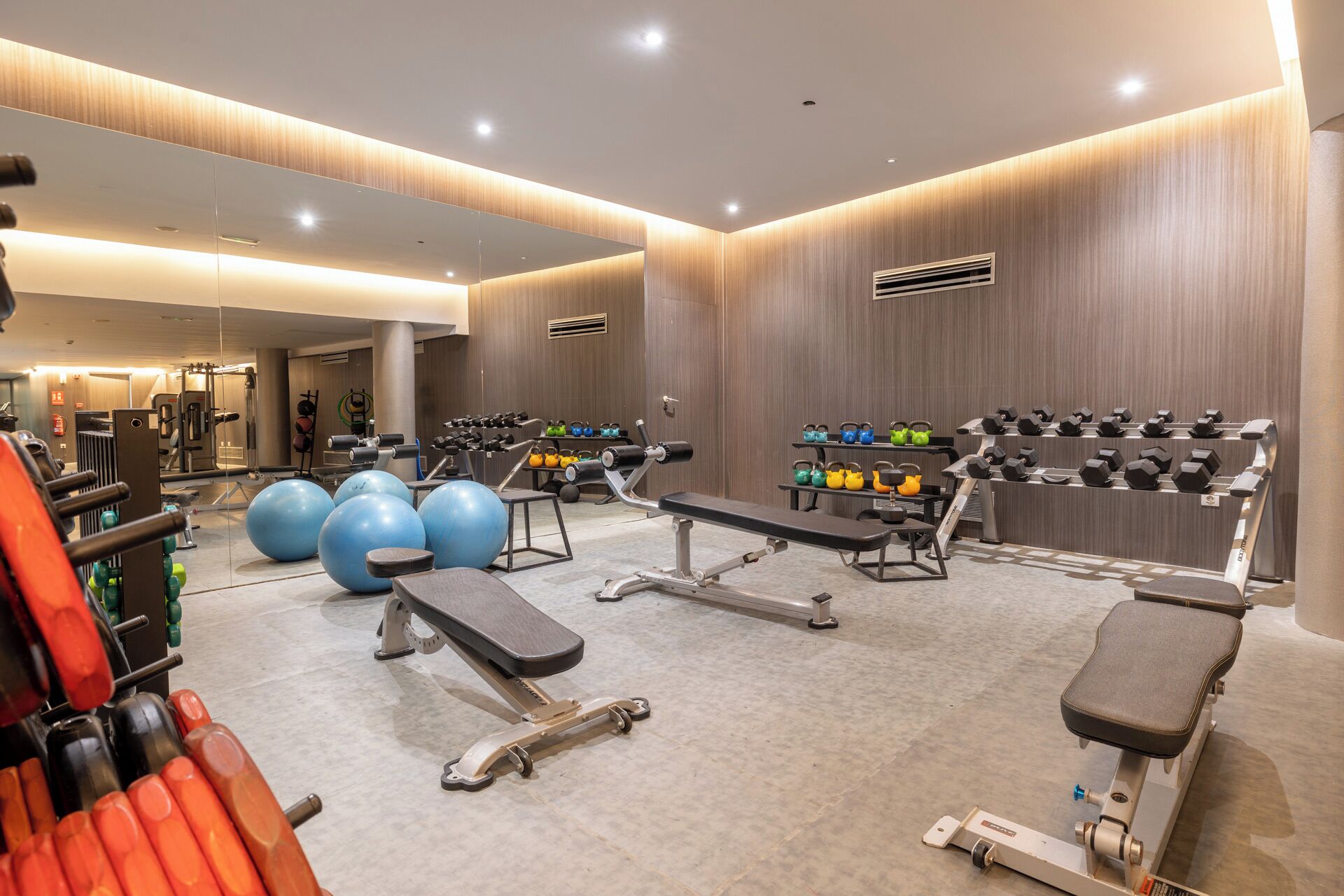 Ein modernes Fitnessstudio mit verschiedenen Trainingsgeräten, darunter Laufbänder, Kraftgeräte und Kurzhanteln.