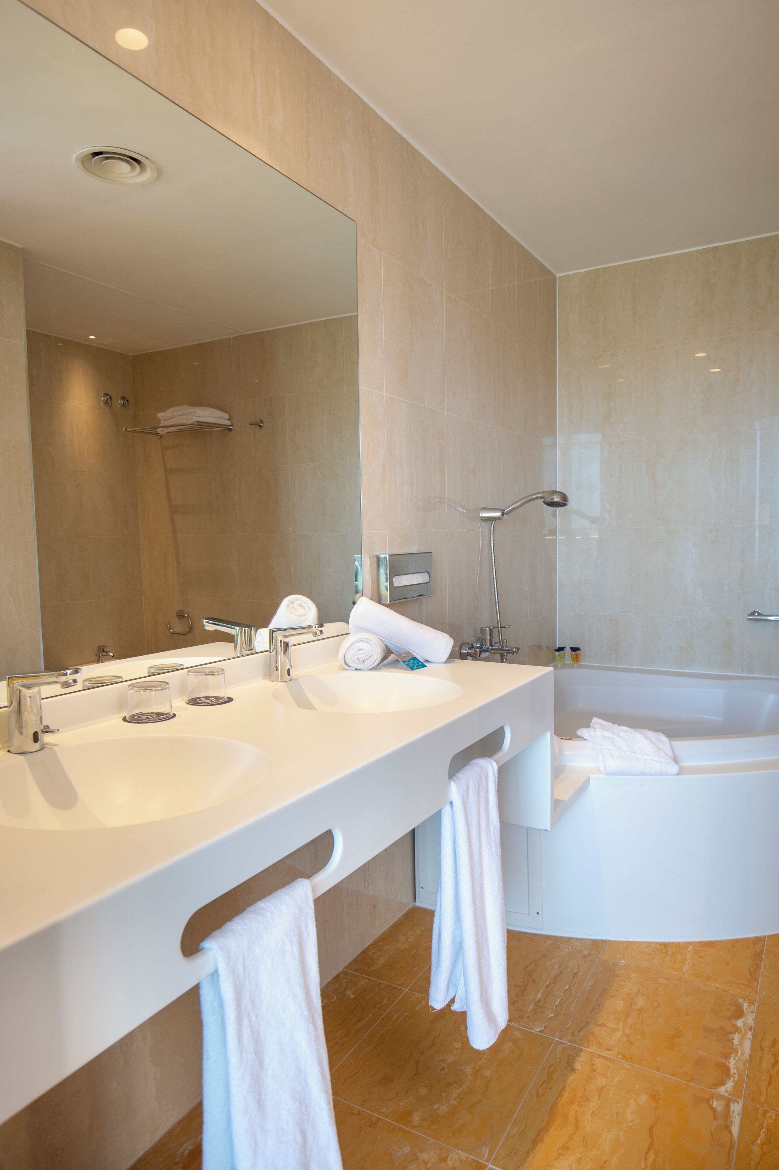 Un bagno moderno con due lavabi, uno specchio grande, una doccia e una vasca da bagno.