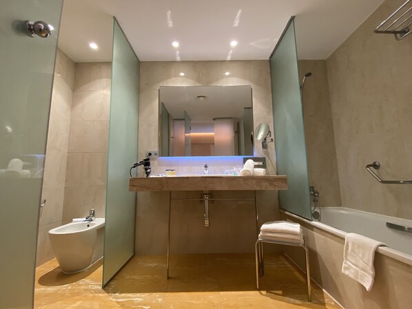 A modern bathroom with a bidet, a sink with a mirror, and a bathtub. - Hotel BCL Levante Club & Spa - Adults only (Benidorm)