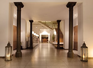 A spacious hallway with marble flooring, large wooden columns, and a staircase leading to upper floors. - Onix Rambla (Barcelona)