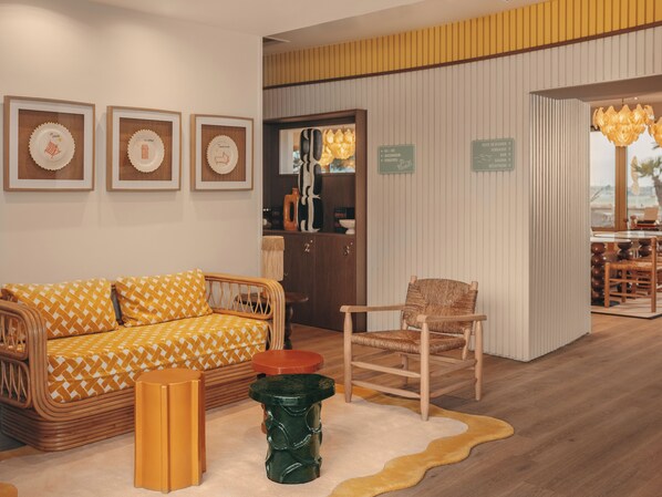 A room with a sofa, chair, framed artwork, and a rug.