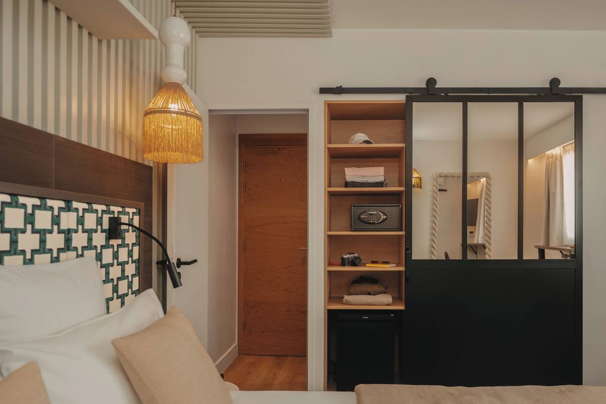A bedroom with a bed, a bedside lamp, a wardrobe, and a mirror.