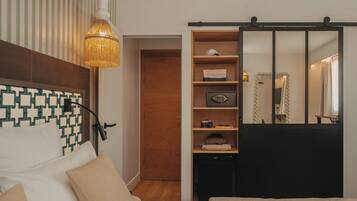 A bedroom with a bed, a bedside lamp, a wardrobe, and a mirror.