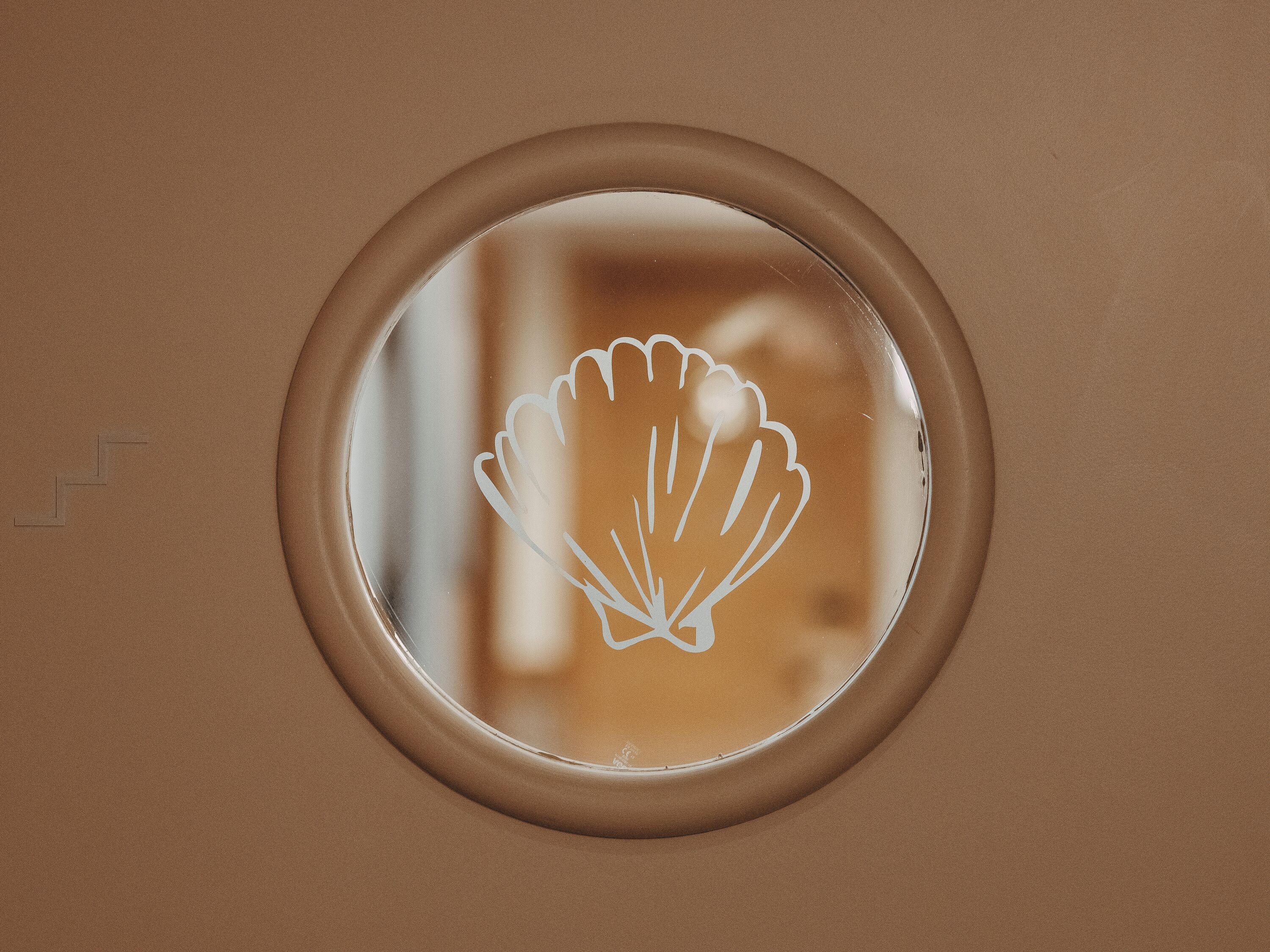 A circular window with a scalloped edge, likely part of a building's exterior.