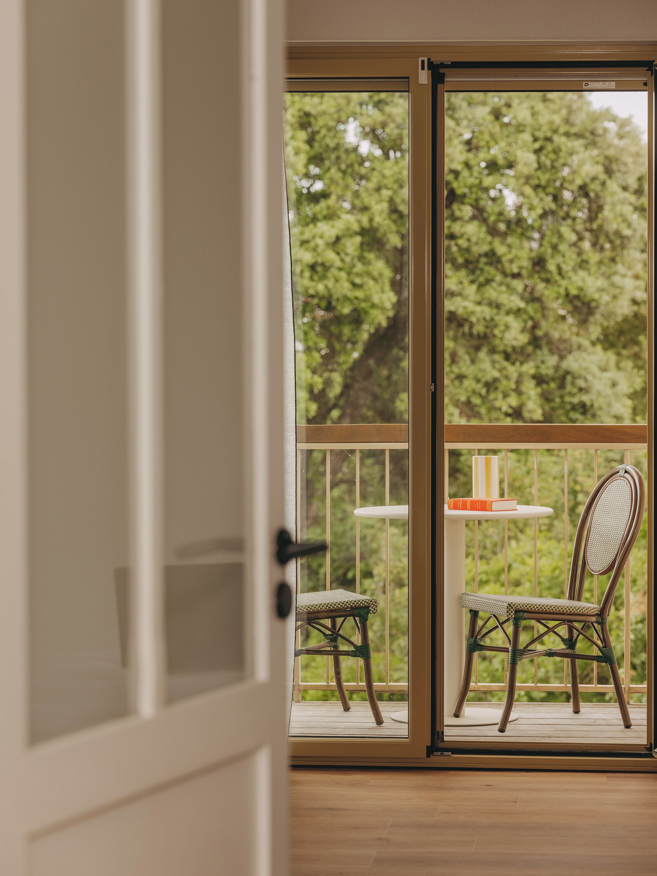 A room with a sliding glass door leading to an outdoor balcony with a wicker chair and a small table.