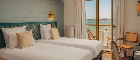 Een hotelkamer met twee bedden, een balkon en een eethoek.