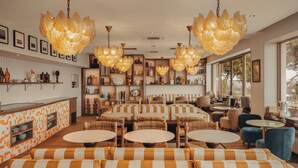 Een modern interieur met gestreepte banken, ronde tafels en decoratieve verlichting.