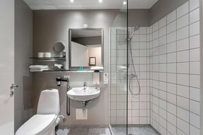 Un baño moderno con inodoro, lavamanos y ducha con mampara de vidrio.
