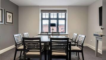 A dining area with a table and chairs, a window with blinds, and framed pictures on the wall.