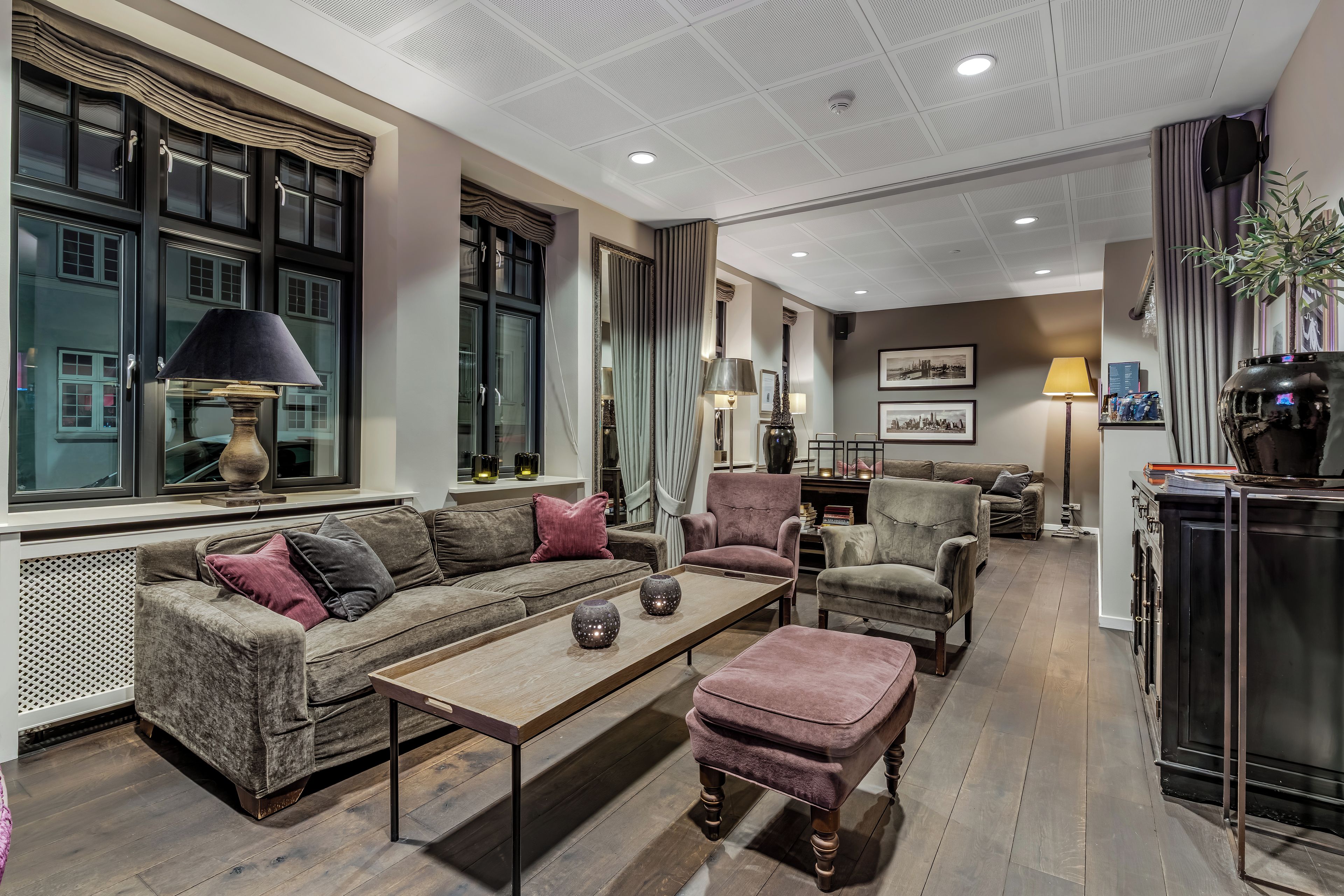 A well-lit living room with a sofa, armchairs, a coffee table, and a fireplace.