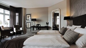 Habitación de hotel con una cama grande, un escritorio, una silla y una ventana con cortinas.