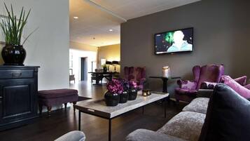 Ein modernes Wohnzimmer mit Fernseher, gemütlicher Sitzgelegenheit, einem Couchtisch mit Vasen und einem dunklen Holzboden.
