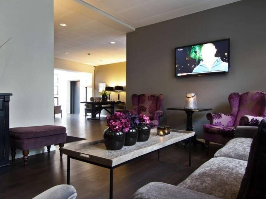 Ein modernes Wohnzimmer mit Fernseher, gemütlicher Sitzgelegenheit, einem Couchtisch mit Vasen und einem dunklen Holzboden.