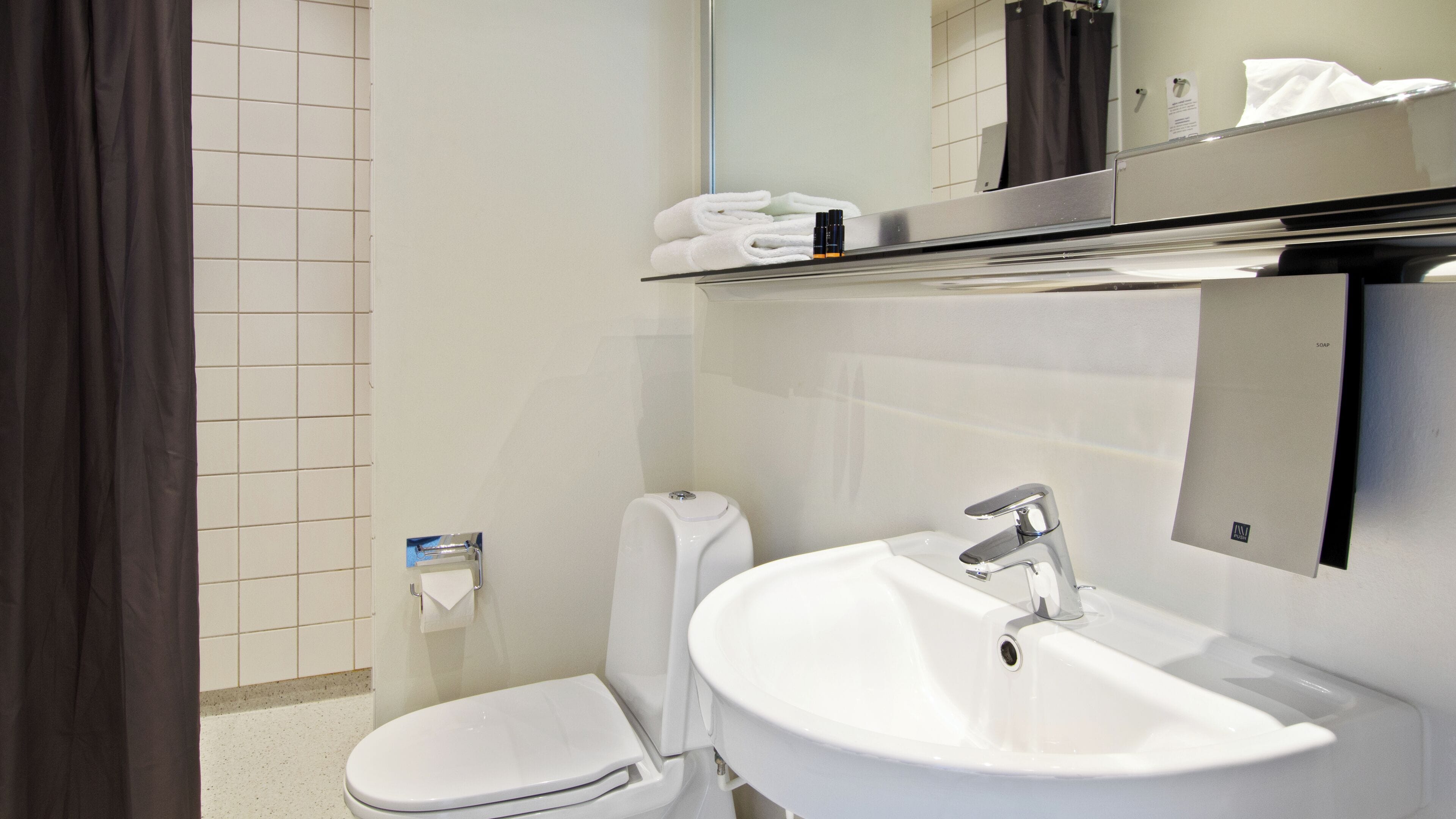 A modern bathroom with a toilet, sink, and mirror.