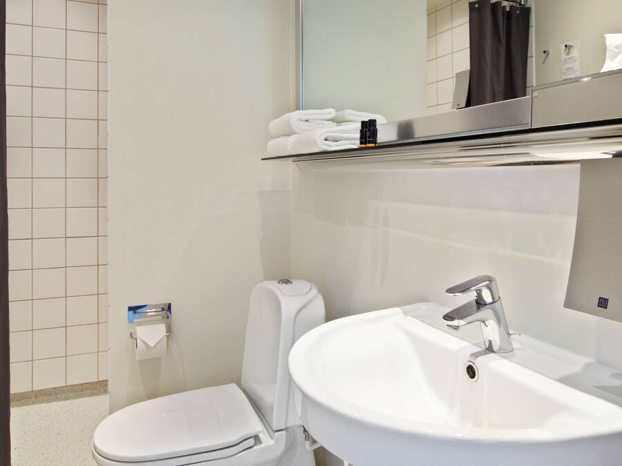 A modern bathroom with a toilet, sink, and mirror.