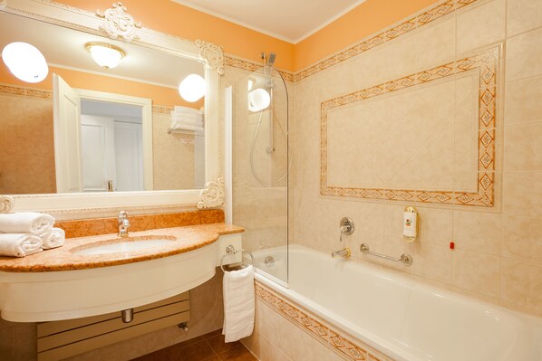 A bathroom with a sink, mirror, and bathtub.