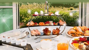 A breakfast buffet with various pastries, fruits, and beverages on a table with a scenic outdoor view. - Gardaland Hotel (Castelnuovo del Garda)