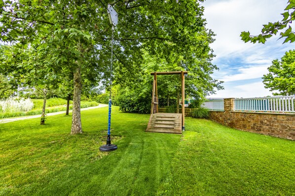 Un jardin bien entretenu, agrémenté d’une balançoire en bois, d’un muret en pierre et d’un chemin dallé.