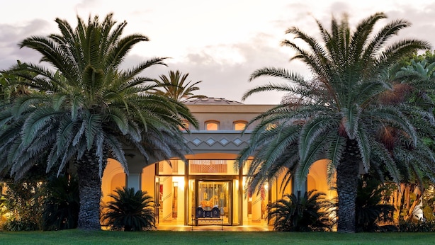 A well-lit building with a symmetrical facade, palm trees, and a clear sky.