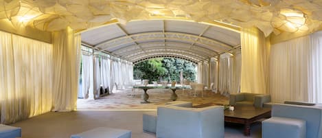 Un espacio interior amplio con un techo alto y arqueado, y una zona de estar central con sofás y una mesa de centro.