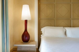Una habitación de hotel con cama, mesita de noche con lámpara y pared con diseño geométrico.
