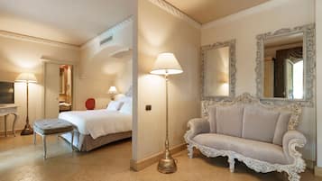 Una habitación de hotel con una cama, un sofá, una lámpara, un espejo y una mesita.