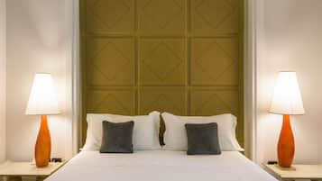 A hotel room with a neatly made bed, two bedside lamps, and a headboard with a geometric pattern.