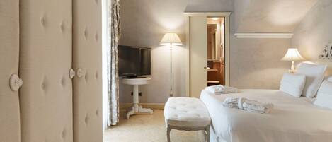 A hotel room with a large bed, a bedside table, a television, and a lamp.