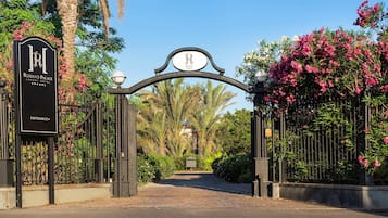 Entrada com portão para um hotel de luxo, com placa indicando o nome e a classificação por estrelas.