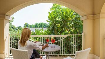 A balcony with a white railing, a round table, and two wicker chairs.