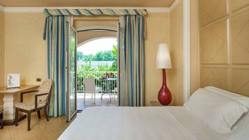 Habitación de hotel con cama, escritorio, silla, lámpara y vistas al exterior.