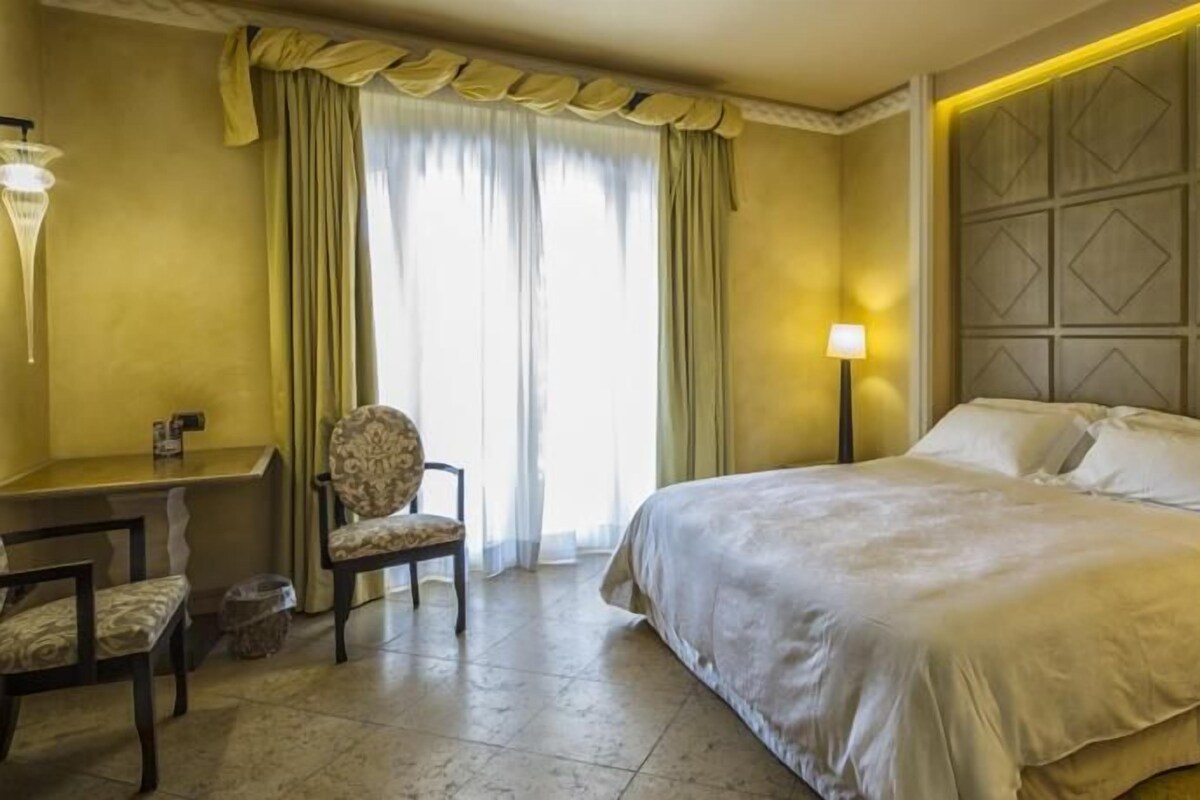 Una habitación de hotel con una cama, un escritorio, una silla y una lámpara.