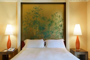 Una camera d'albergo con un letto, due comodini, un telefono e due lampade.
