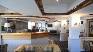 A hotel lobby with a reception desk, a sofa, a dining area, and a fireplace. - Park Hotel (Montrose)