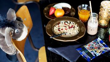 Una mesa de comedor con un plato de cereal, un vaso de jugo de naranja, una botella de leche y un peluche.
