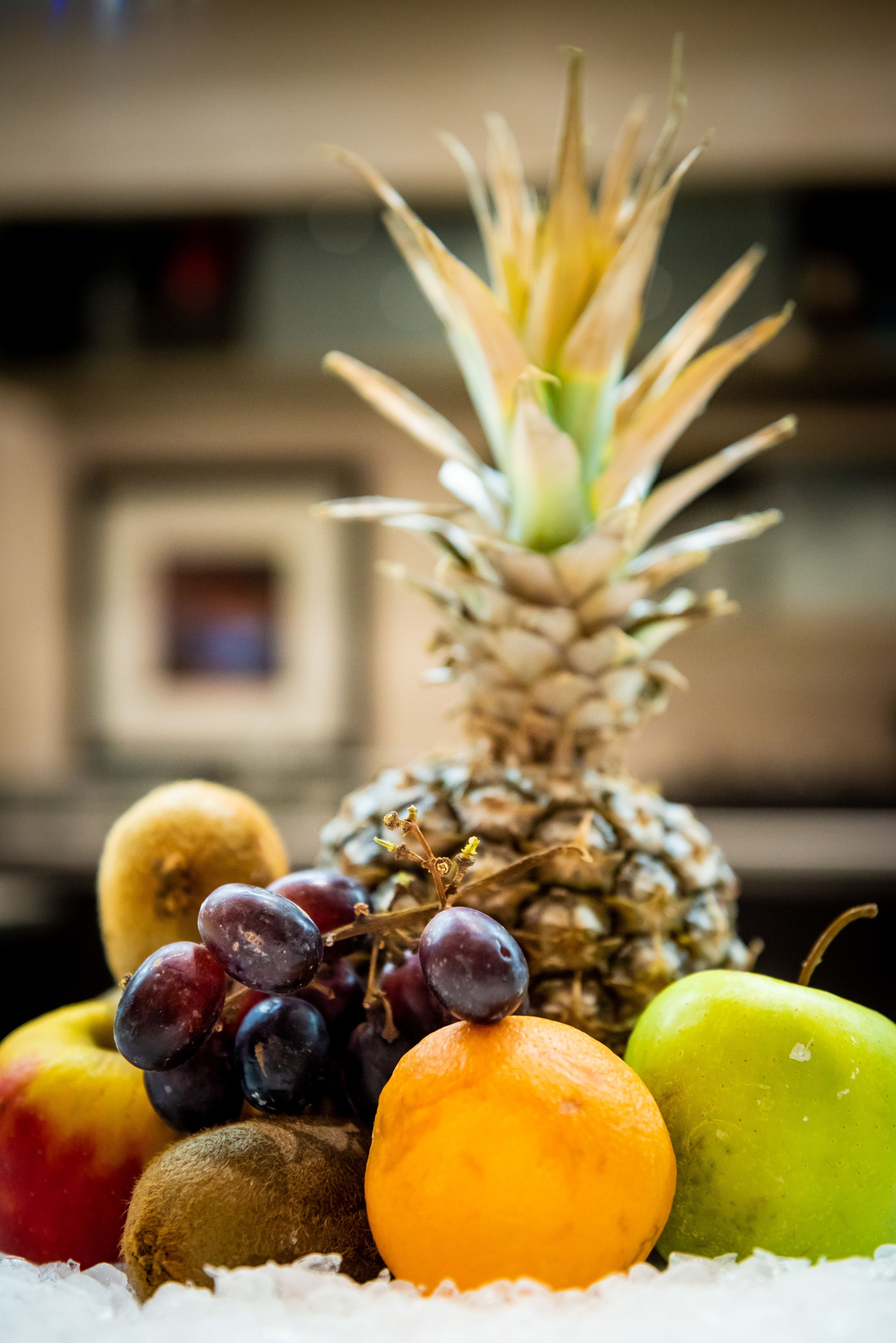 Un ananas entouré de différents fruits, le tout posé sur un lit de glace.