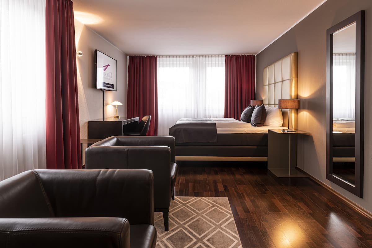 Une chambre d’hôtel moderne équipée d’un lit, d’un bureau, d’une chaise et d’un grand miroir.