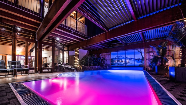 A swimming pool with a view of a mountain range, wooden beams, and lounge chairs. - Mauritius Hotel & Therme (Cologne)