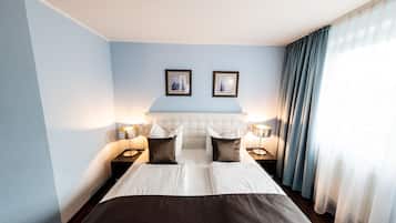 A hotel room with a large bed, two bedside tables with lamps, a headboard, and two framed pictures on the wall.