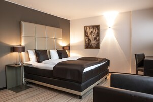 Una habitación de hotel moderna con una cama grande, mesitas de noche, un escritorio y una silla.