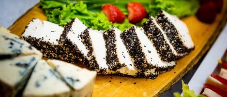 Une planche en bois garnie de fromage en tranches, de fraises et de laitue.