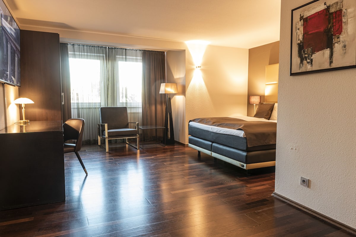 Une chambre d’hôtel avec un lit, un bureau, une chaise et une lampe.