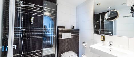 A modern bathroom with a glass-enclosed shower, a white sink, and a mirror above it.