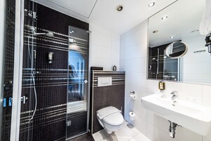 A modern bathroom with a glass-enclosed shower, a white sink, and a mirror above it.