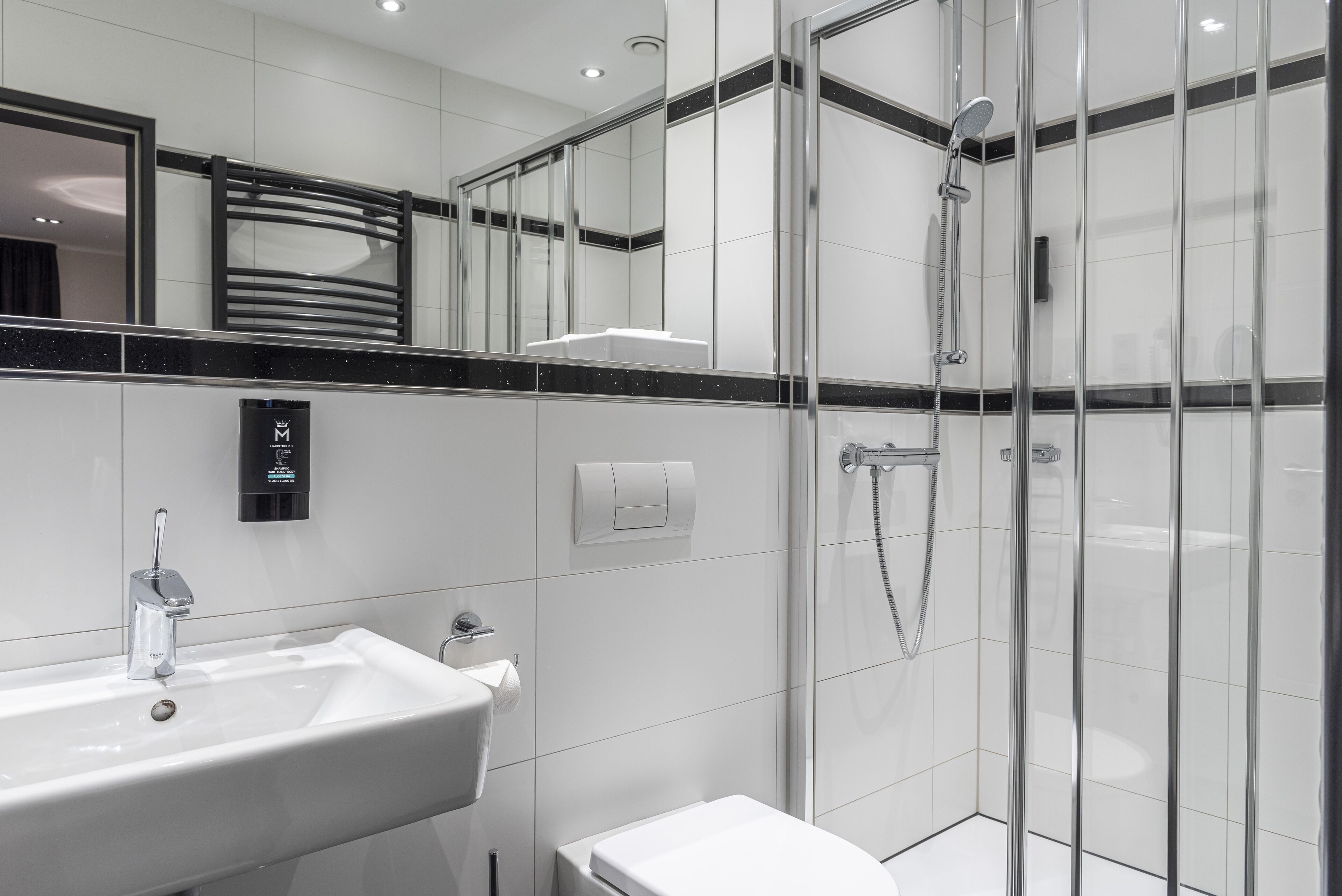 A modern bathroom with a glass-enclosed shower, a white sink, and a toilet.