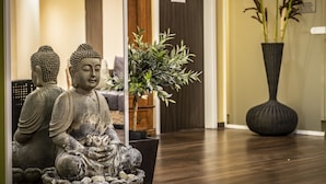 A statue of a seated figure in a room with a wooden floor and a sign for a massage service. - Mauritius Hotel & Therme (Cologne)