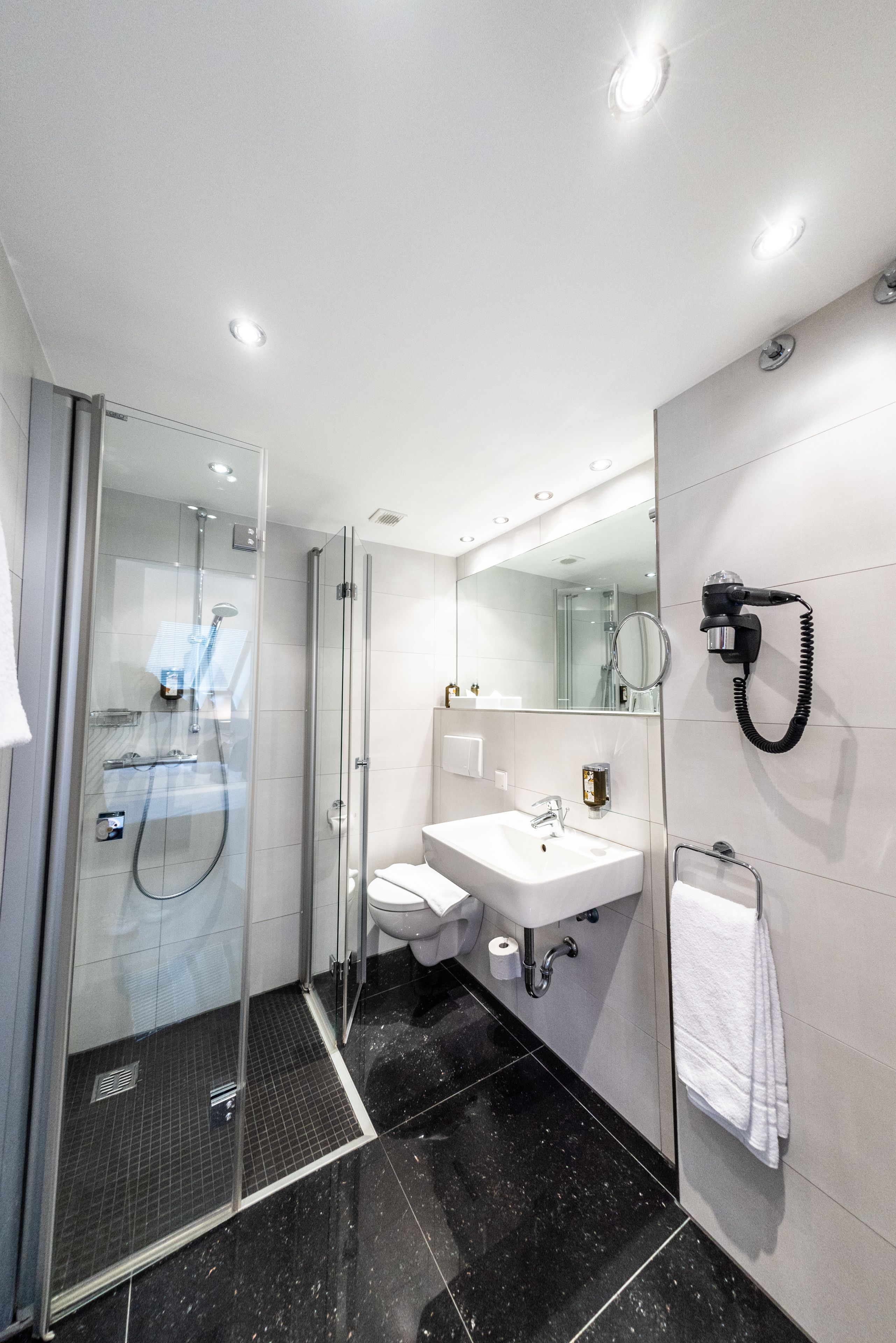 Un baño moderno con ducha acristalada, lavabo blanco y espejo.